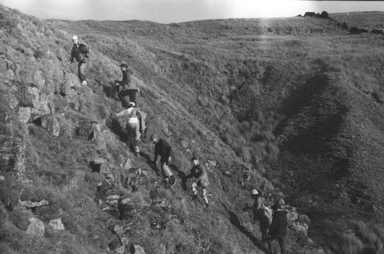 5 people climbing a hill in black and white